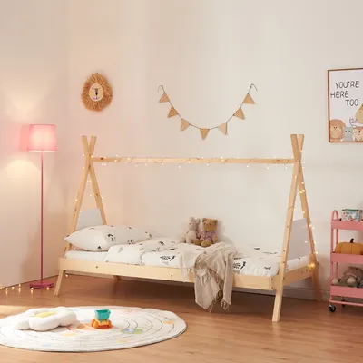 A child's bedroom with a teepee-style bed, a pink floor lamp, and decorative elements.