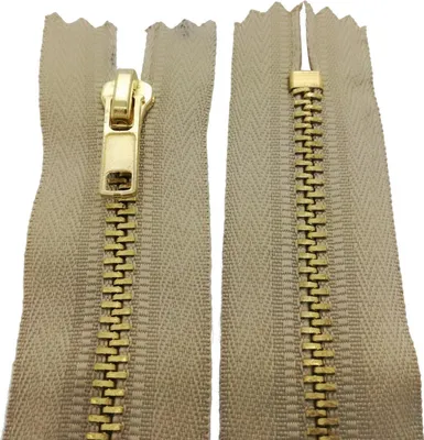A close-up view of a beige zipper with gold-colored metal teeth and slider.