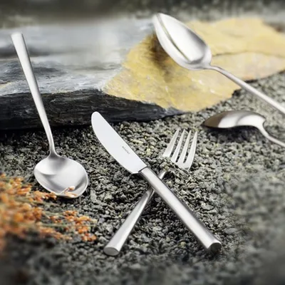 Cutlery arranged on a textured surface with rocks and gravel.