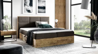 A bedroom scene featuring a large boxspring bed, bedside table, and artwork.