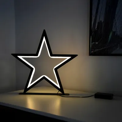 A star-shaped LED lamp sits on a white surface, casting a warm glow.