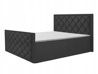 A studio shot of a black upholstered bed frame with a mattress and headboard.