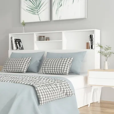 A bedroom scene with a white headboard with shelves above a bed.