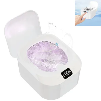 A white ultrasonic cleaner with its lid open, filled with purple-tinted water, cleaning dental aligners and a ring.