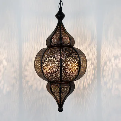 A black oriental lantern hanging against a white background, casting intricate shadows.