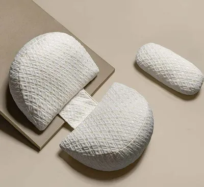 Three white pillows with a diamond-stitched pattern are arranged on a tan and beige surface.