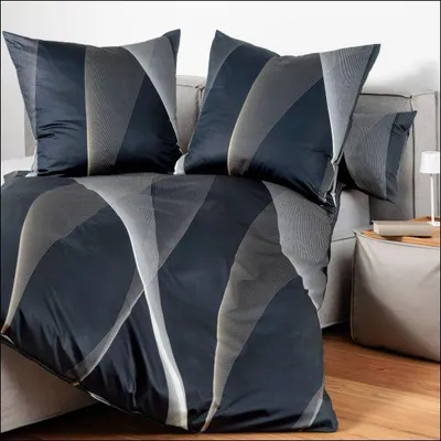 A bed with pillows and a duvet cover with a geometric pattern.