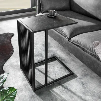 A black marble-top side table with a slatted metal frame sits next to a gray sofa in a modern living room setting.