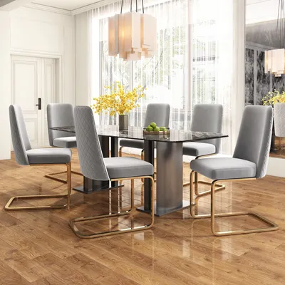 A dining room set with a glass-top table and six gray upholstered chairs with gold metal legs.
