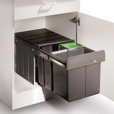A pull-out trash and recycling bin system installed inside a kitchen cabinet.