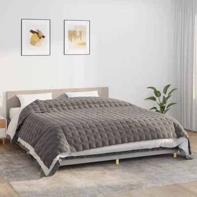 A bed with a gray quilted blanket.