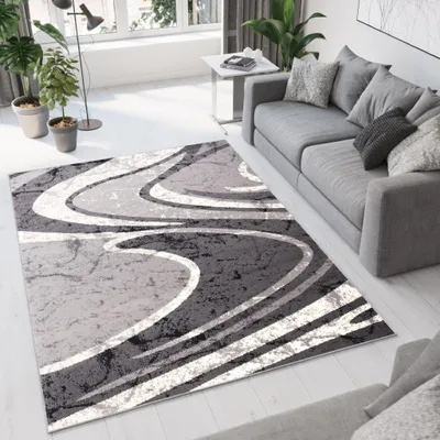 A modern living room with a gray sofa, a rug, and plants.