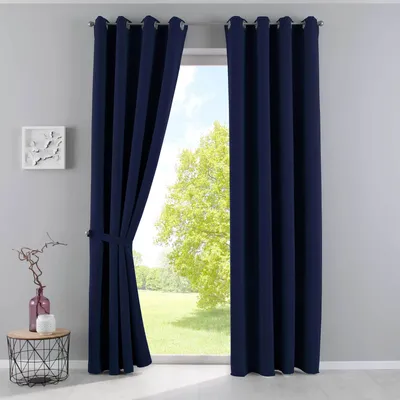 A pair of navy blue curtains are shown tied back on the left side, revealing a bright, green outdoor scene through a window. A small side table with decorative items is visible on the left.