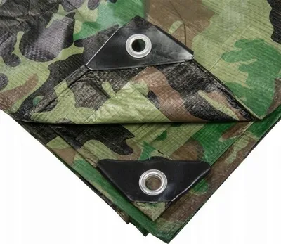 A close-up view of a camouflage tarp, showing reinforced corners with grommets.