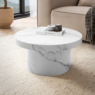 A round coffee table with a marble pattern sits on a textured rug in a living room setting.