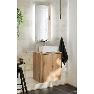 A modern bathroom vanity with a wooden cabinet, white sink, and a lit mirror.