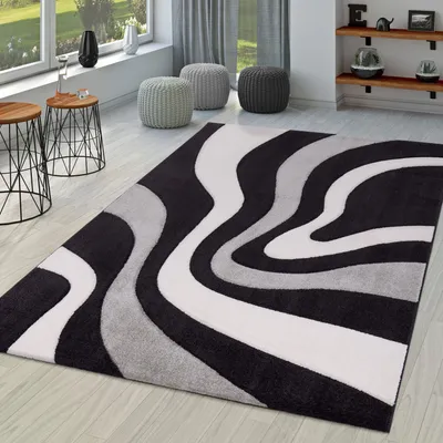 A modern living room with a rug, side tables, and ottomans.