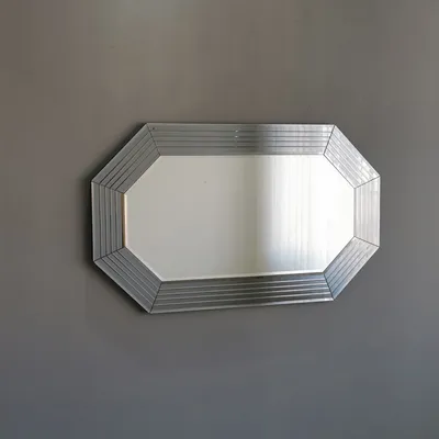 A rectangular mirror with an octagonal frame hangs on a gray wall.