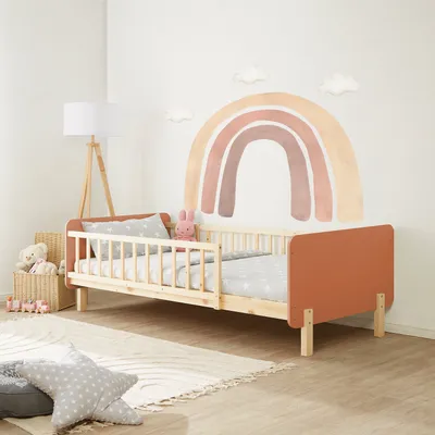 A child's bedroom with a wooden bed decorated with a rainbow mural on the wall.