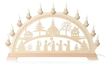Ein traditioneller Schwibbogen aus Holz zeigt eine winterliche Szene mit einer Kirche Bäumen und Häusern sowie Figuren die sich unter einem Bogen aus Kerzenlichtern befinden