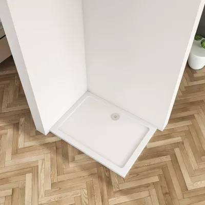 A white shower tray is shown in a corner of a bathroom, with a wooden floor.