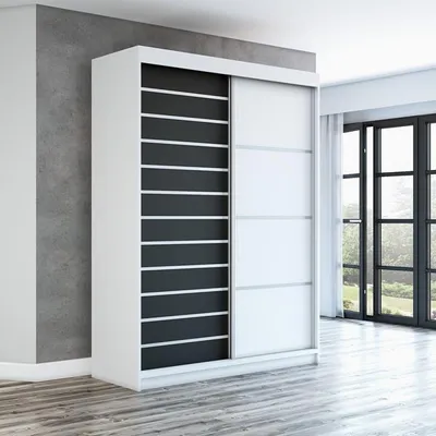 A modern white wardrobe with black and white sliding doors stands in a room with a concrete wall and wooden floor.