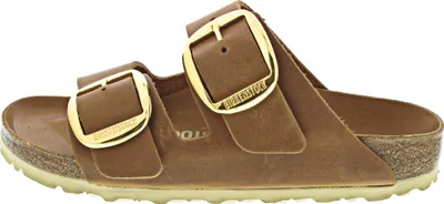 A side view of a brown Birkenstock sandal with large gold buckles.