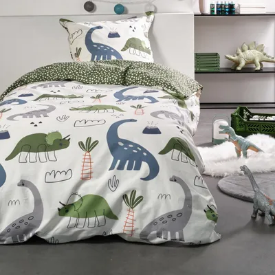 A children's bedding set with a dinosaur theme is displayed on a bed.