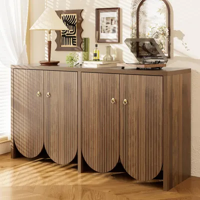 A wooden sideboard with fluted doors and brass handles, decorated with a lamp, books, and a record player.