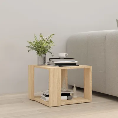 A wooden side table with books and a vase of flowers next to a couch.