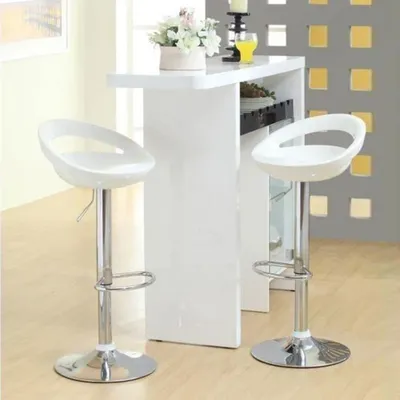 Two white bar stools and a white bar counter with flowers and a drink on it.