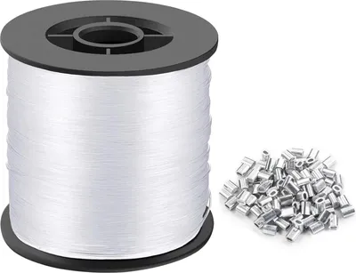 A spool of white nylon thread and a pile of silver crimp beads on a white background.