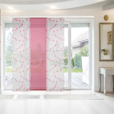 Panel curtains with a pink and white floral pattern are installed on a sliding glass door, looking out onto a garden.