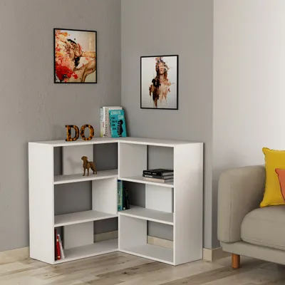A corner bookshelf filled with books and decorative items, next to a sofa with cushions.