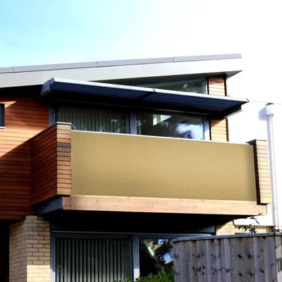 A balcony with a tan privacy screen and wooden accents on a modern building.