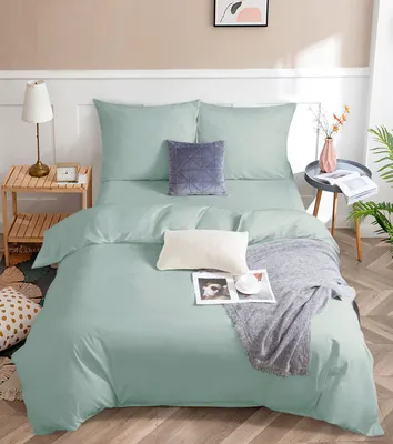 A neatly made bed with mint green bedding, pillows, and a throw blanket.