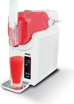 A slush machine with a glass of slush in front of it.