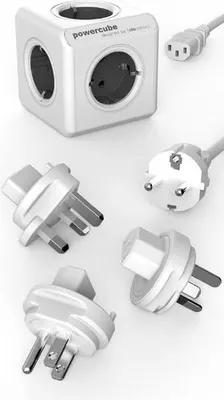 A white power cube with multiple outlets and several different plug adapters are arranged around it on a white background.