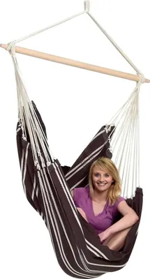 A woman is sitting in a striped hammock chair.