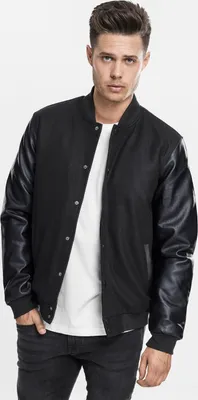 A man wearing a black college jacket and jeans against a white background.