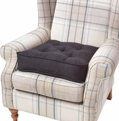 A dark grey seat cushion is placed on a beige and blue plaid armchair.