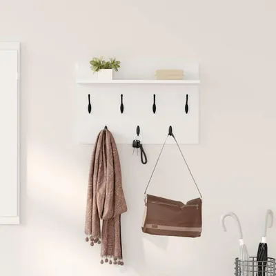 A white wall-mounted shelf with hooks, holding a scarf, keys, and a handbag. There are also two umbrellas in a basket on the right.