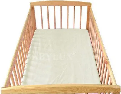 A wooden crib with a cream-colored sheet.
