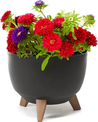 A black planter with wooden legs filled with colorful flowers.