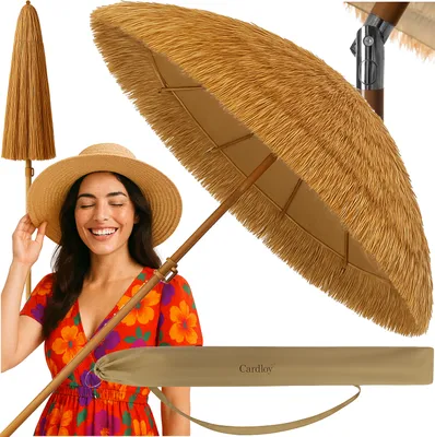 A woman wearing a straw hat and a floral dress is smiling next to a closed and open Hawaiian-style beach umbrella.