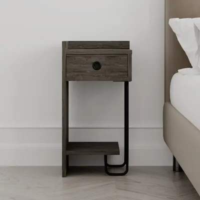 A modern nightstand with a drawer and an open shelf, placed next to a bed.