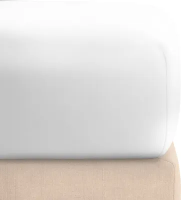 A close-up view of a white fitted sheet on top of a beige bed base.