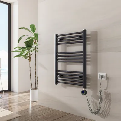A modern bathroom setting with a black electric towel warmer mounted on a light-colored tiled wall, next to a tall potted plant.