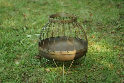 A metal fire pit sits on a grassy lawn.