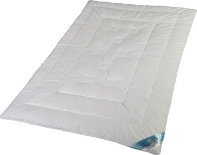 A white comforter is laid out on a white background.
